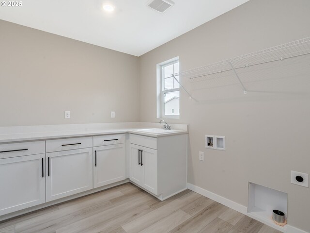 kitchen featuring light stone counters, white cabinets, light hardwood / wood-style flooring, and an island with sink