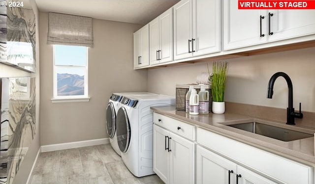 washroom with cabinets, light hardwood / wood-style flooring, sink, and washer and clothes dryer