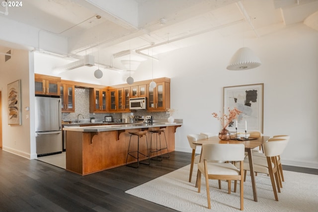 kitchen featuring brown cabinets, a peninsula, stainless steel appliances, and glass insert cabinets