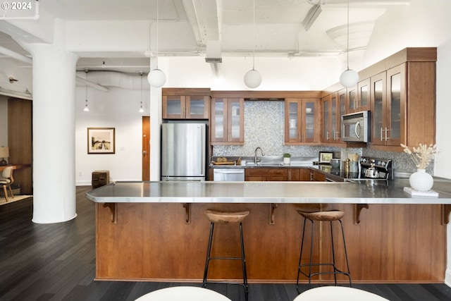 kitchen with kitchen peninsula, a breakfast bar area, backsplash, pendant lighting, and appliances with stainless steel finishes