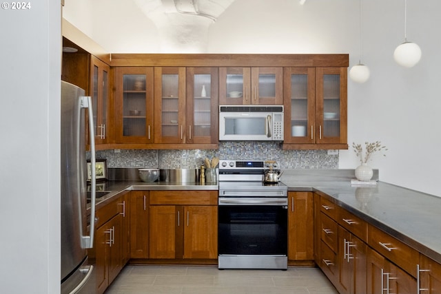 kitchen featuring kitchen peninsula, pendant lighting, tasteful backsplash, dark stone counters, and appliances with stainless steel finishes