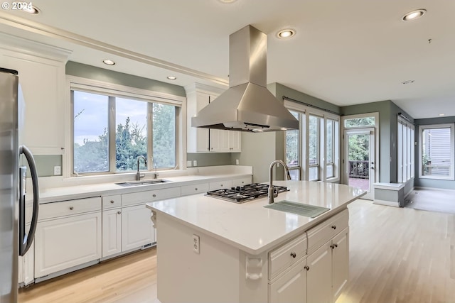 kitchen featuring white cabinets, an island with sink, sink, island exhaust hood, and light hardwood / wood-style flooring