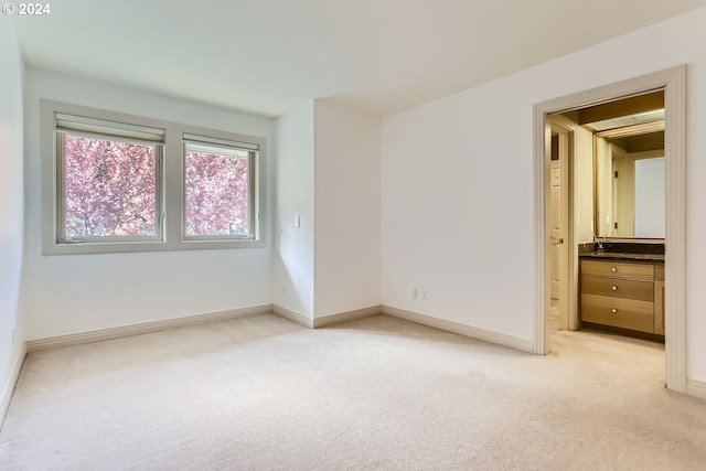 unfurnished bedroom with connected bathroom and light colored carpet