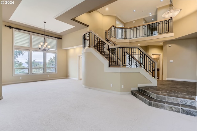 stairway with a towering ceiling, carpet floors, and a notable chandelier