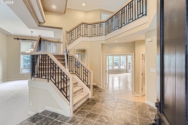 stairs with an inviting chandelier, a high ceiling, carpet, and a healthy amount of sunlight