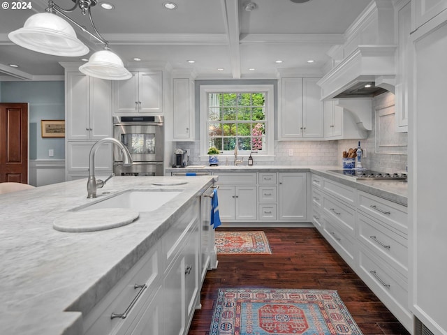 kitchen with hanging light fixtures, light stone countertops, black electric cooktop, white cabinets, and sink