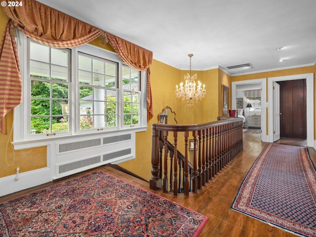 hall with hardwood / wood-style flooring, a chandelier, crown molding, and radiator heating unit