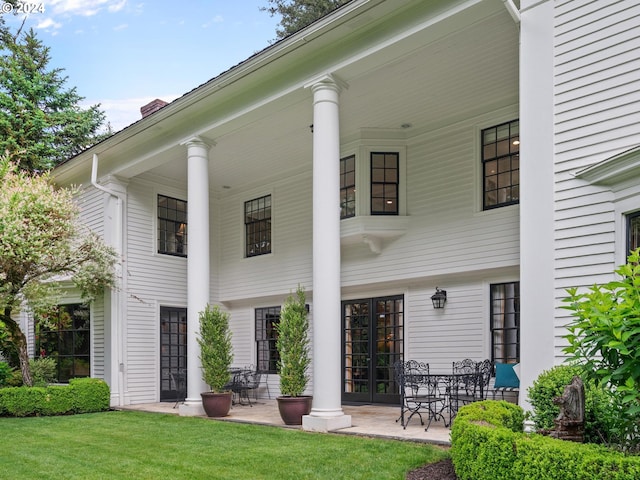 rear view of house featuring french doors and a lawn