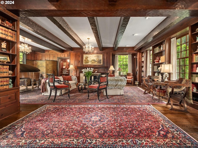 living area with an inviting chandelier, beam ceiling, wooden walls, and dark hardwood / wood-style floors