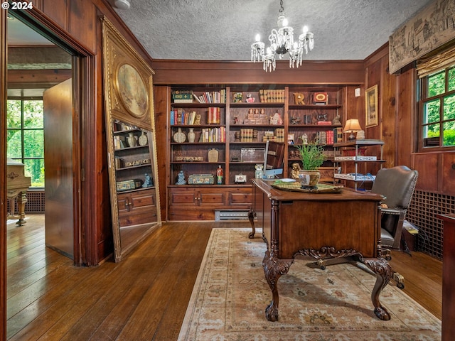 office space featuring a textured ceiling, hardwood / wood-style floors, wood walls, and a chandelier