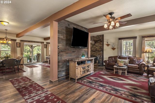 living room featuring wood walls, dark wood-type flooring, beam ceiling, and ceiling fan