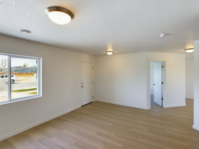 unfurnished room featuring light hardwood / wood-style floors and a textured ceiling