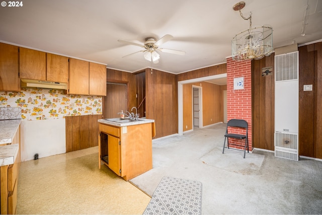 kitchen featuring ceiling fan with notable chandelier, wood walls, sink, and hanging light fixtures