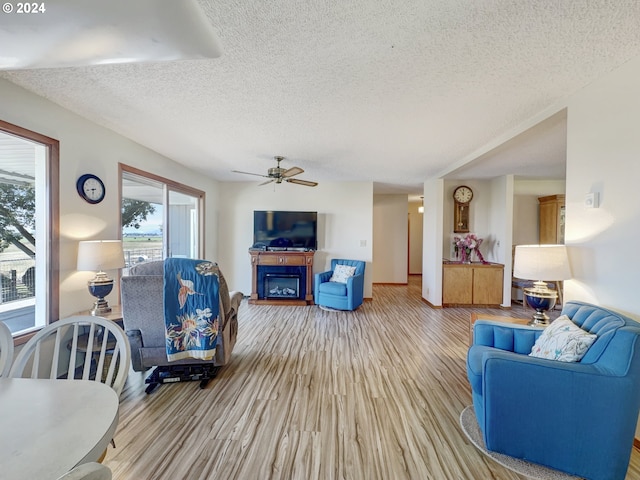 living room featuring a textured ceiling, ceiling fan, and light hardwood / wood-style flooring