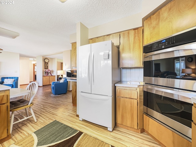 kitchen featuring light hardwood / wood-style floors, tasteful backsplash, a textured ceiling, stainless steel double oven, and white fridge