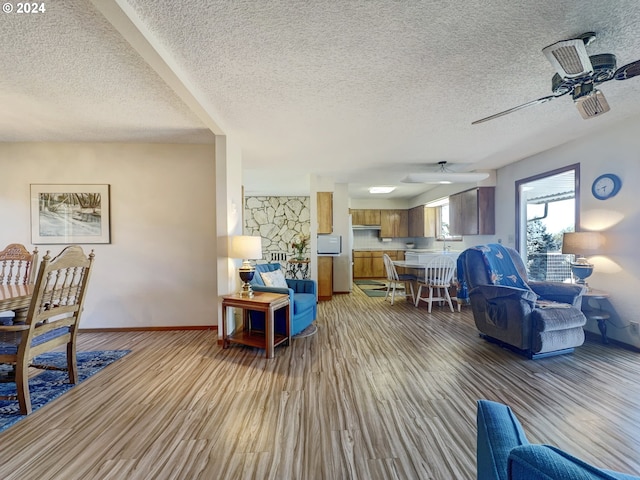 living room with light wood-type flooring, a textured ceiling, and ceiling fan