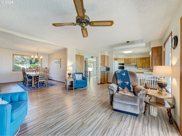 living room featuring a textured ceiling, light hardwood / wood-style floors, and ceiling fan with notable chandelier