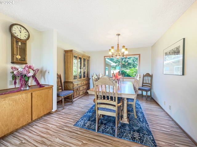 dining space featuring light hardwood / wood-style floors, a chandelier, and a textured ceiling