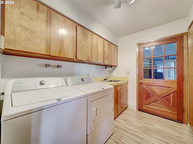 laundry room with cabinets, light hardwood / wood-style floors, separate washer and dryer, and sink