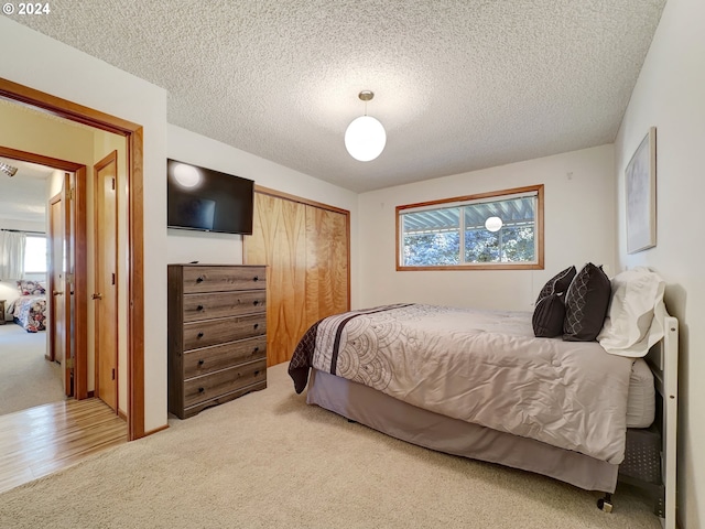 carpeted bedroom with a textured ceiling and a closet