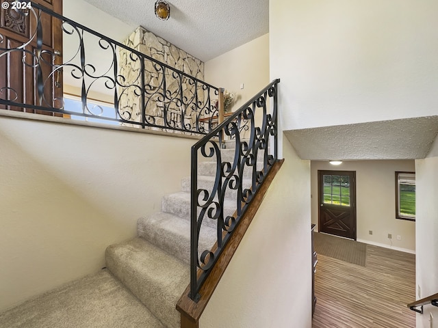 stairway with carpet and a textured ceiling