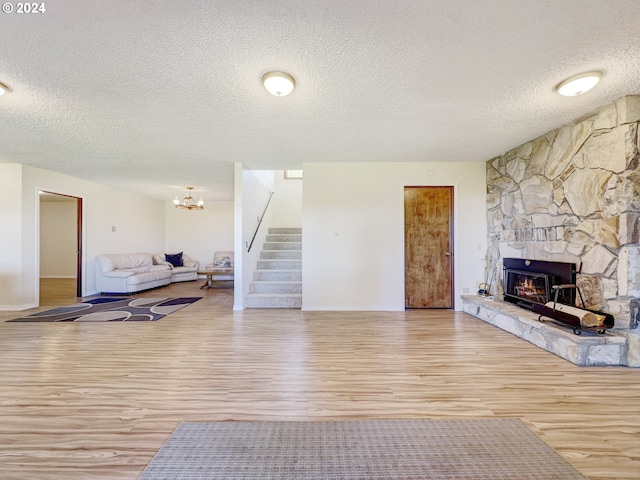 living room featuring light wood-type flooring, a textured ceiling, and a fireplace