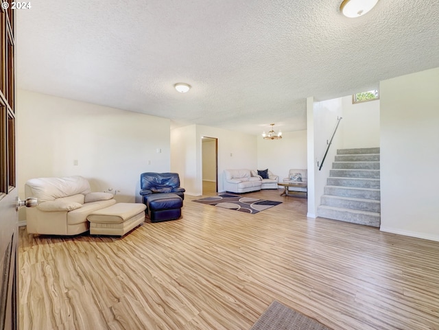 living room with light hardwood / wood-style flooring, a textured ceiling, and a chandelier