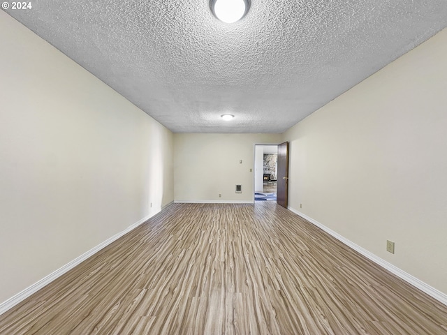 empty room featuring light wood-type flooring and a textured ceiling