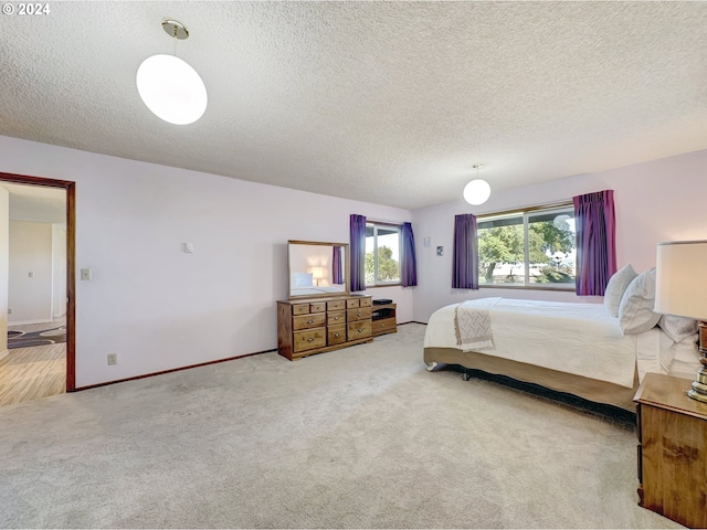 bedroom with a textured ceiling and light carpet