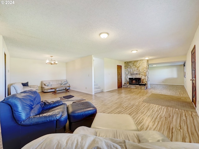 living room featuring a stone fireplace, a textured ceiling, and hardwood / wood-style flooring