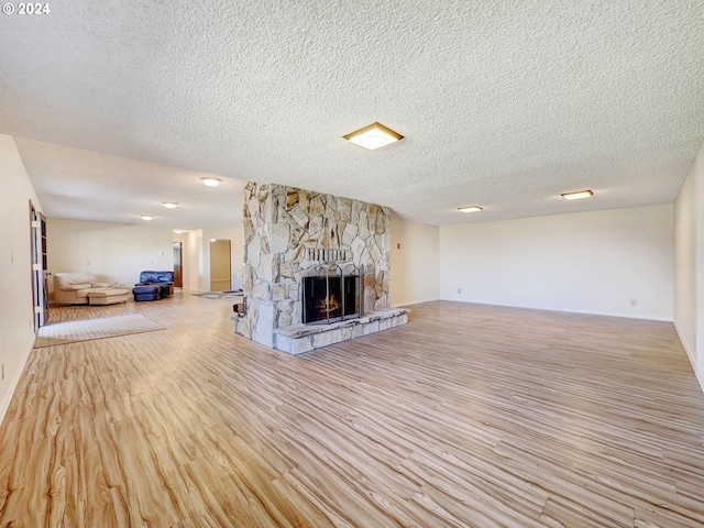 unfurnished living room featuring light wood-type flooring, a textured ceiling, and a fireplace