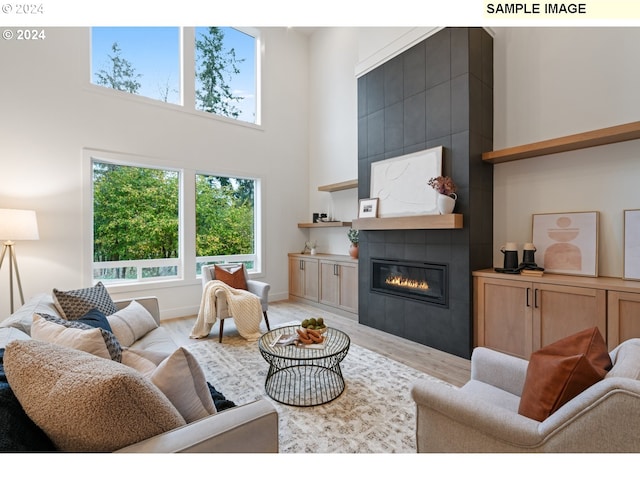 living room with wood-type flooring, a high ceiling, and a tile fireplace