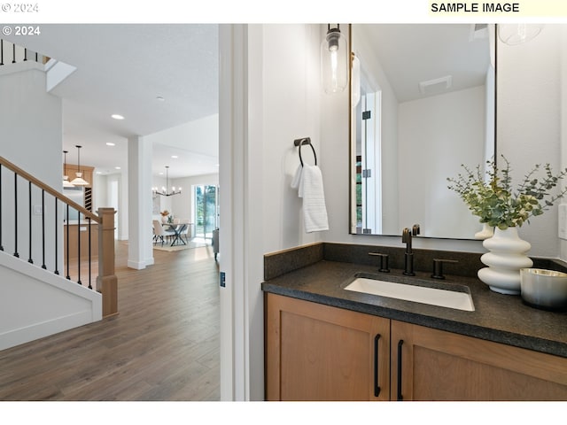 bathroom with vanity, wood-type flooring, and an inviting chandelier