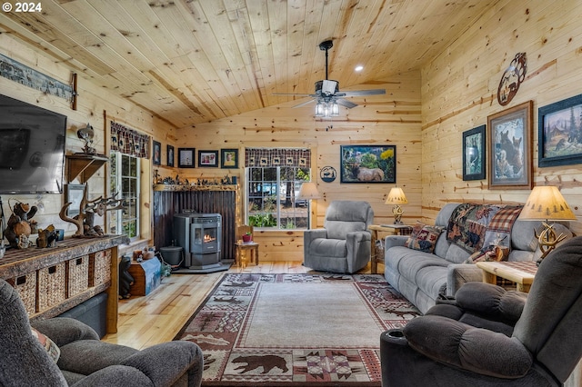 living room with wood ceiling, ceiling fan, high vaulted ceiling, light hardwood / wood-style floors, and a wood stove