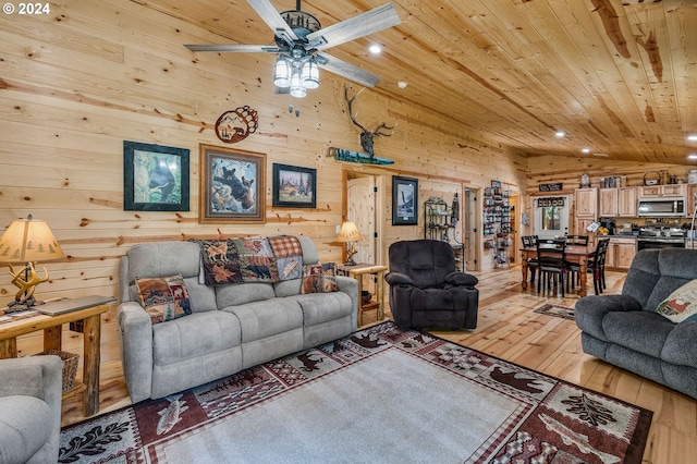 living room featuring wood ceiling, vaulted ceiling, ceiling fan, wooden walls, and light hardwood / wood-style flooring