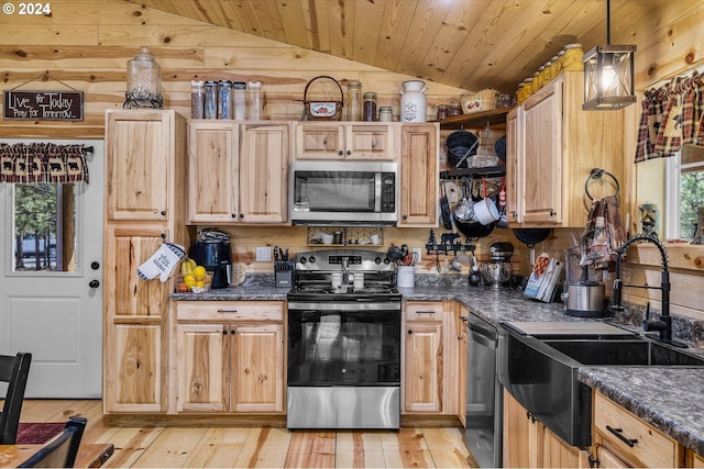 kitchen featuring pendant lighting, sink, vaulted ceiling, light wood-type flooring, and appliances with stainless steel finishes