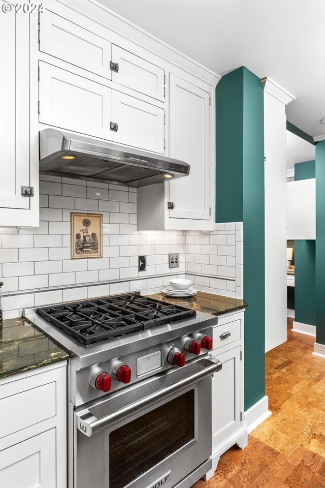 kitchen with white cabinets, decorative backsplash, designer stove, and dark stone counters