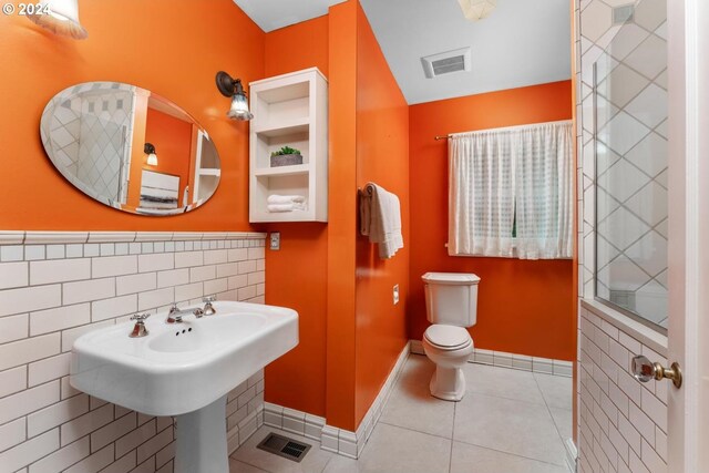 bathroom featuring tile patterned floors, tile walls, and toilet