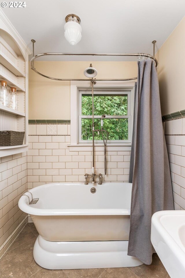 bathroom with a bathtub, tile patterned floors, and tile walls