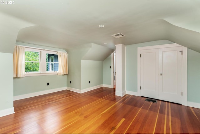 additional living space with hardwood / wood-style flooring and lofted ceiling