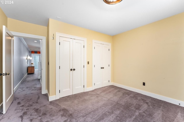 unfurnished bedroom featuring carpet floors and two closets