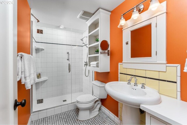 bathroom with tile patterned flooring, backsplash, toilet, and an enclosed shower