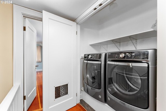 clothes washing area with wood-type flooring and separate washer and dryer