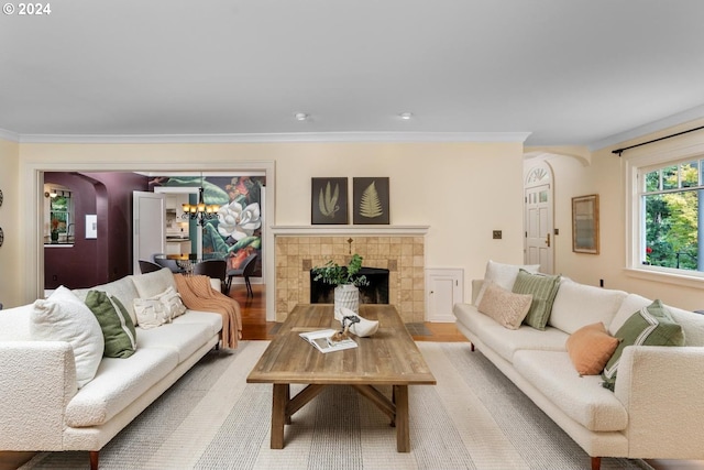 living room with crown molding, a fireplace, an inviting chandelier, and light hardwood / wood-style flooring