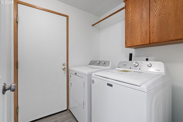 clothes washing area featuring light wood-type flooring, separate washer and dryer, and cabinets