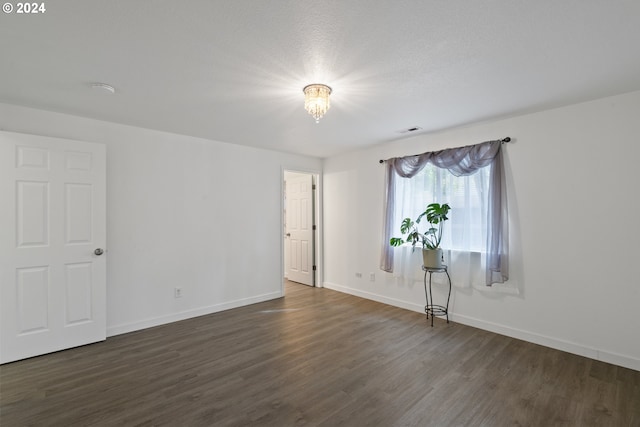 empty room featuring a textured ceiling and dark wood-type flooring