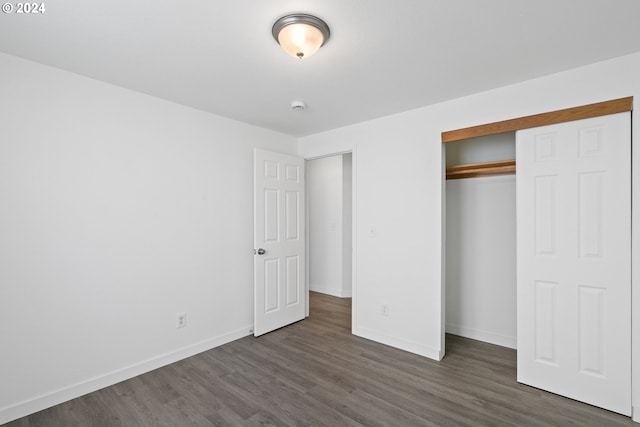 unfurnished bedroom with a closet and dark wood-type flooring