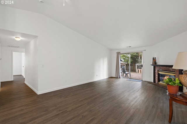 living room featuring dark wood-type flooring, vaulted ceiling, and a fireplace