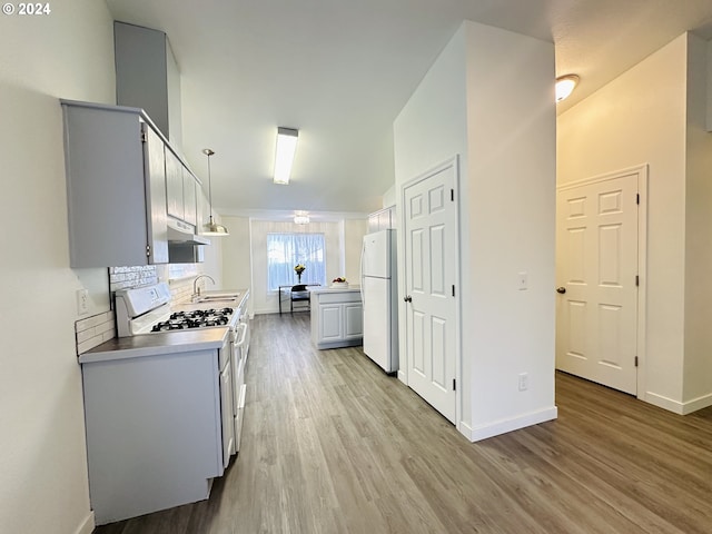 kitchen with decorative backsplash, light hardwood / wood-style flooring, sink, decorative light fixtures, and white appliances