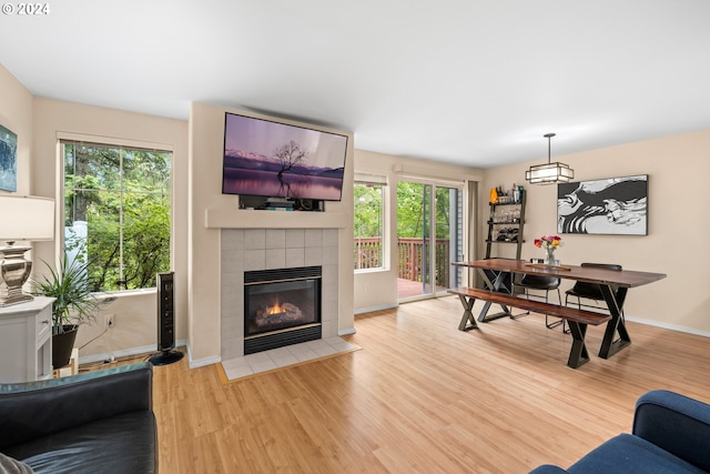 rec room featuring a tile fireplace, a wealth of natural light, and light hardwood / wood-style flooring